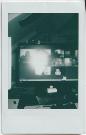 a black and white instant photo of the participants. a large white spot is created by the camera's flash and covers many faces. the rest are very blurry